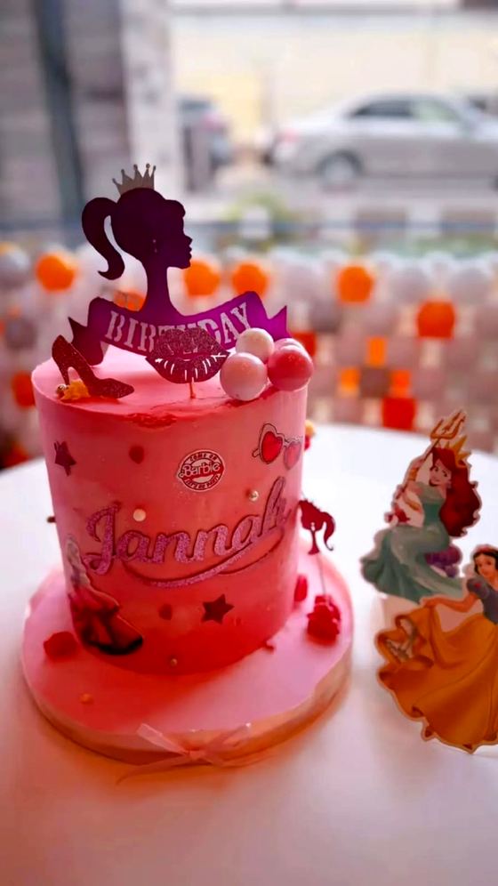A pink character themed birthday cake with a personalised name