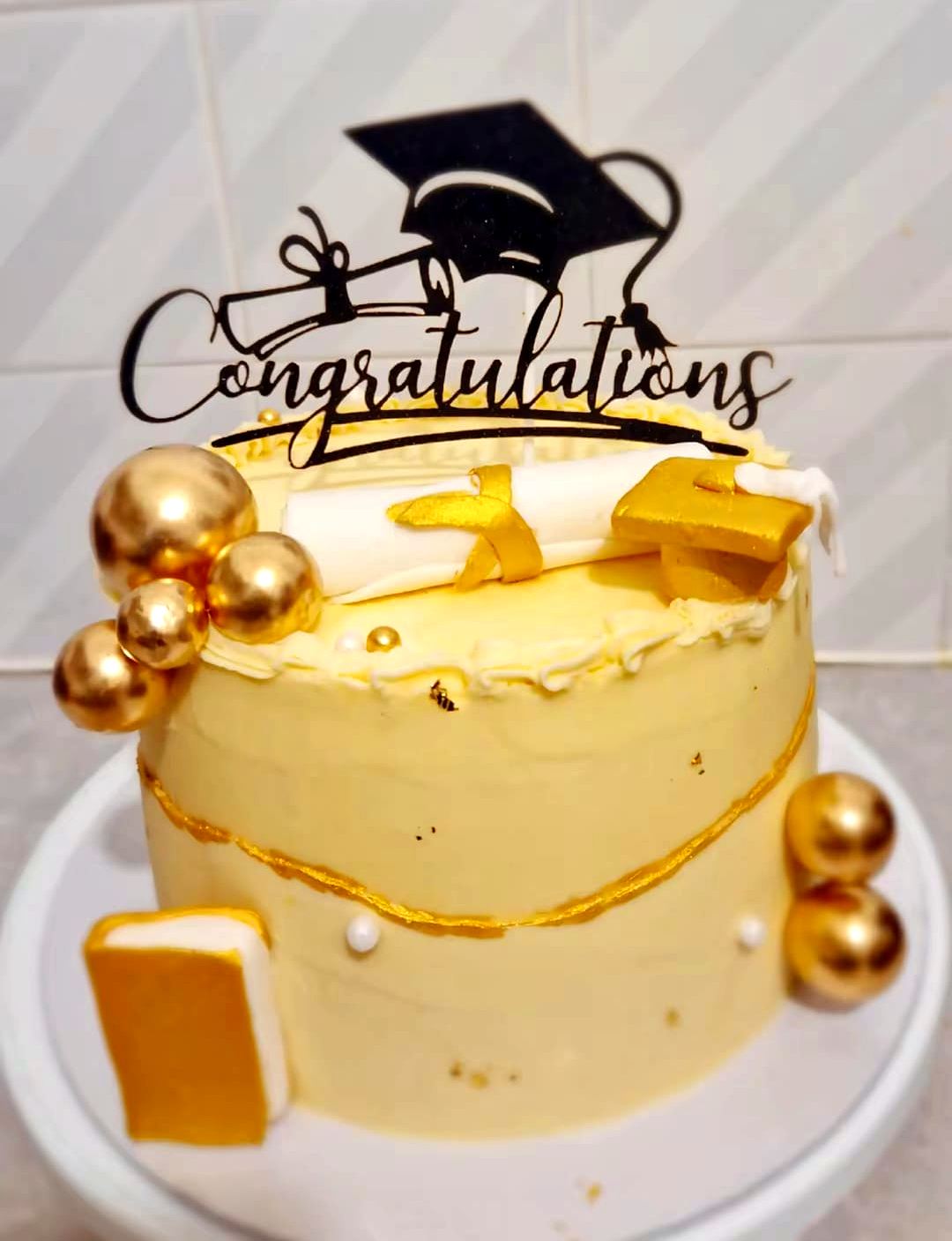 A gold and ivory graduation cake with a congratulations topper