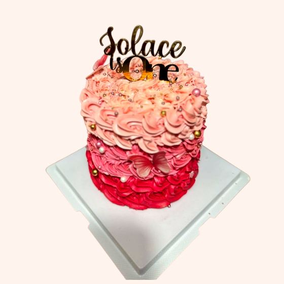 A pink ombre ruffle first birthday cake